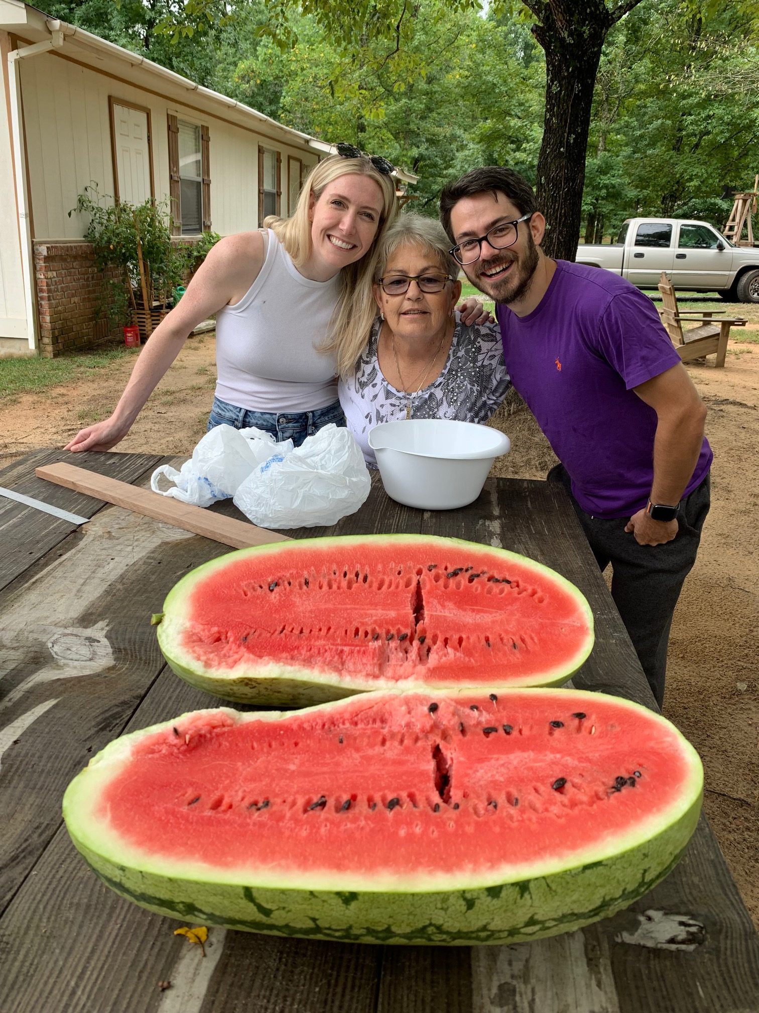 A photo shows Elaine Ross with her son, Skyler Kern, and his wife, Sydney Kern, standing by a picnic table. A cut watermelon rests on the table.