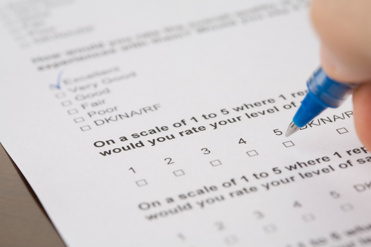 A photo shows a close-up of a survey with check boxes. A hand is filling out the form with a blue pen.