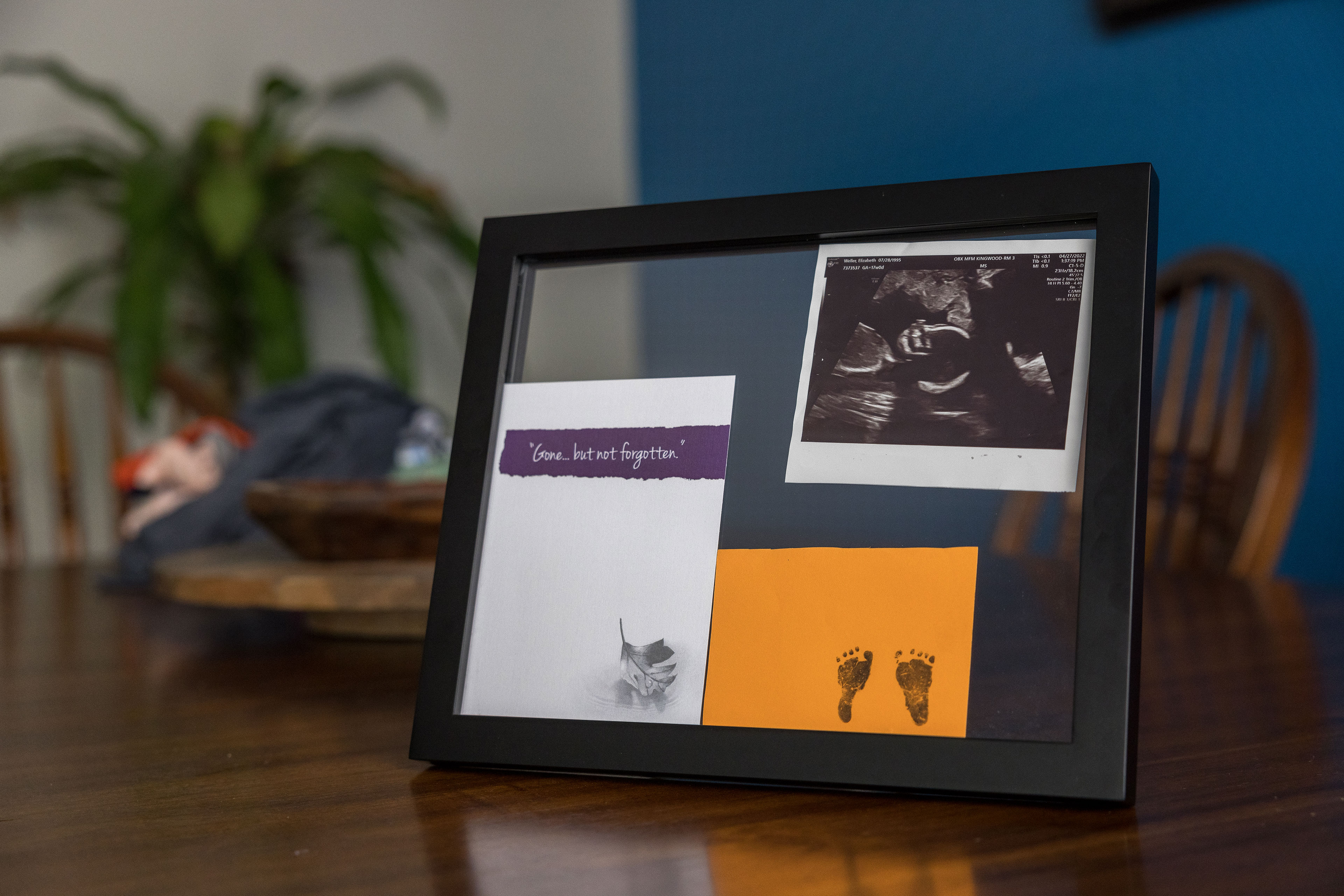 A frame holds a sonogram, a card with small footprints, and a card that says "Gone... but not forgotten."