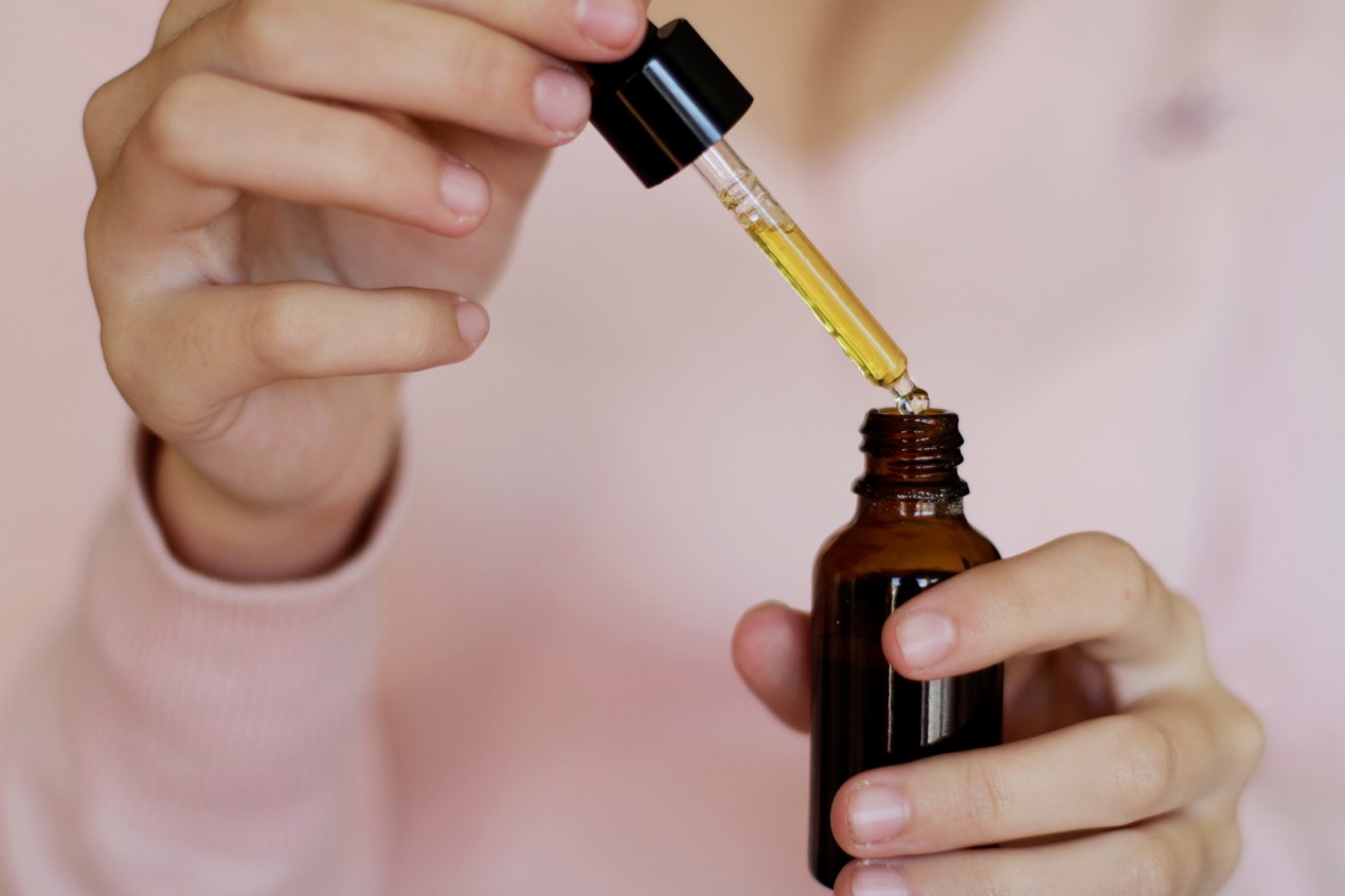 A photo shows a woman holding a vial of oil and a pipette, suggesting it is Delta-8 oil.