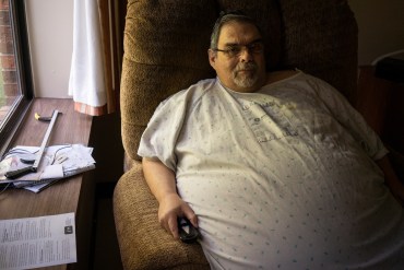 A photo shows Jeff White sitting in the nursing home where he lives, looking at the camera.