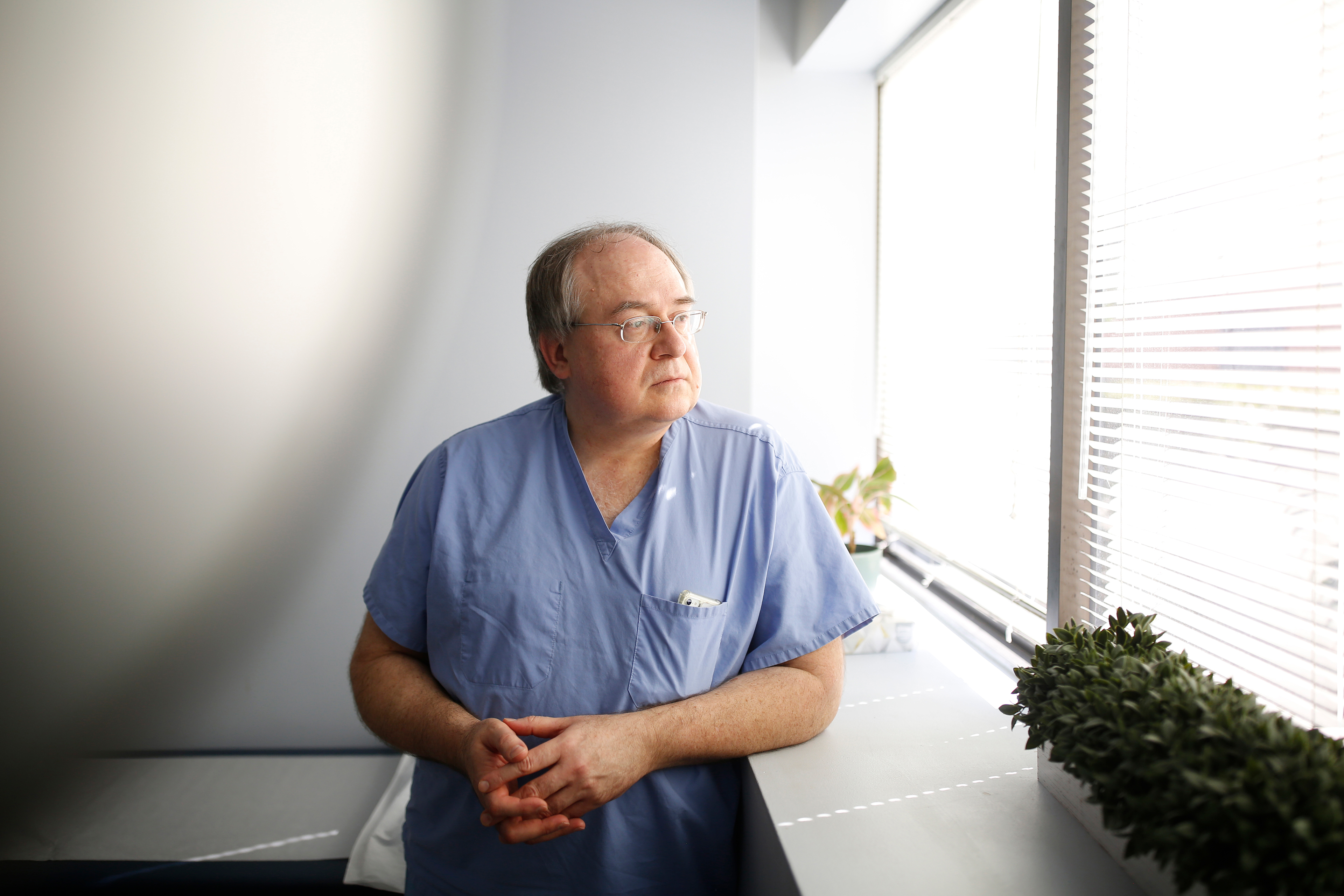 A photo shows Dr. Andrew Bush inside his office. He is looking out of a window to his left.