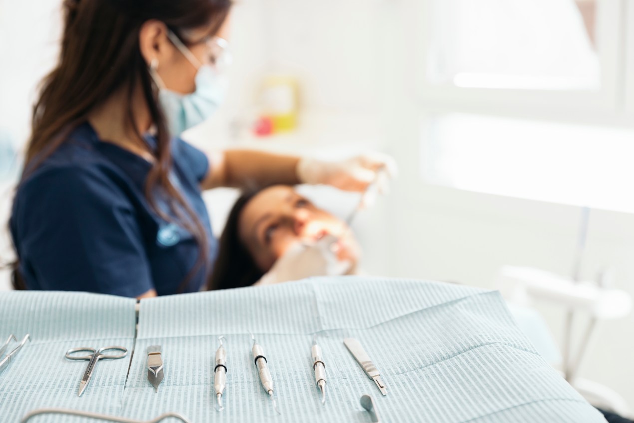 dentist working on a patients mouth with dentistry tools laid out in the foreground