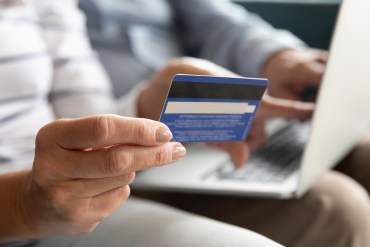 Female holding credit card making online payment, closeup view.