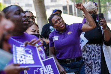 A photo shows Mattie Ruffin chanting with other protesters outside of Los Angeles City Hall. Some hold signs that read, "Fair wages."