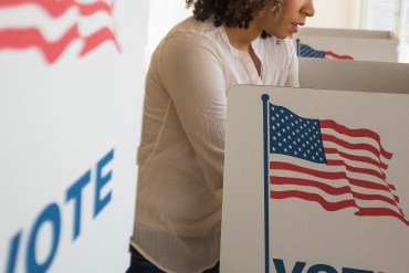 A photo shows a woman filling out a ballot at a polling booth.