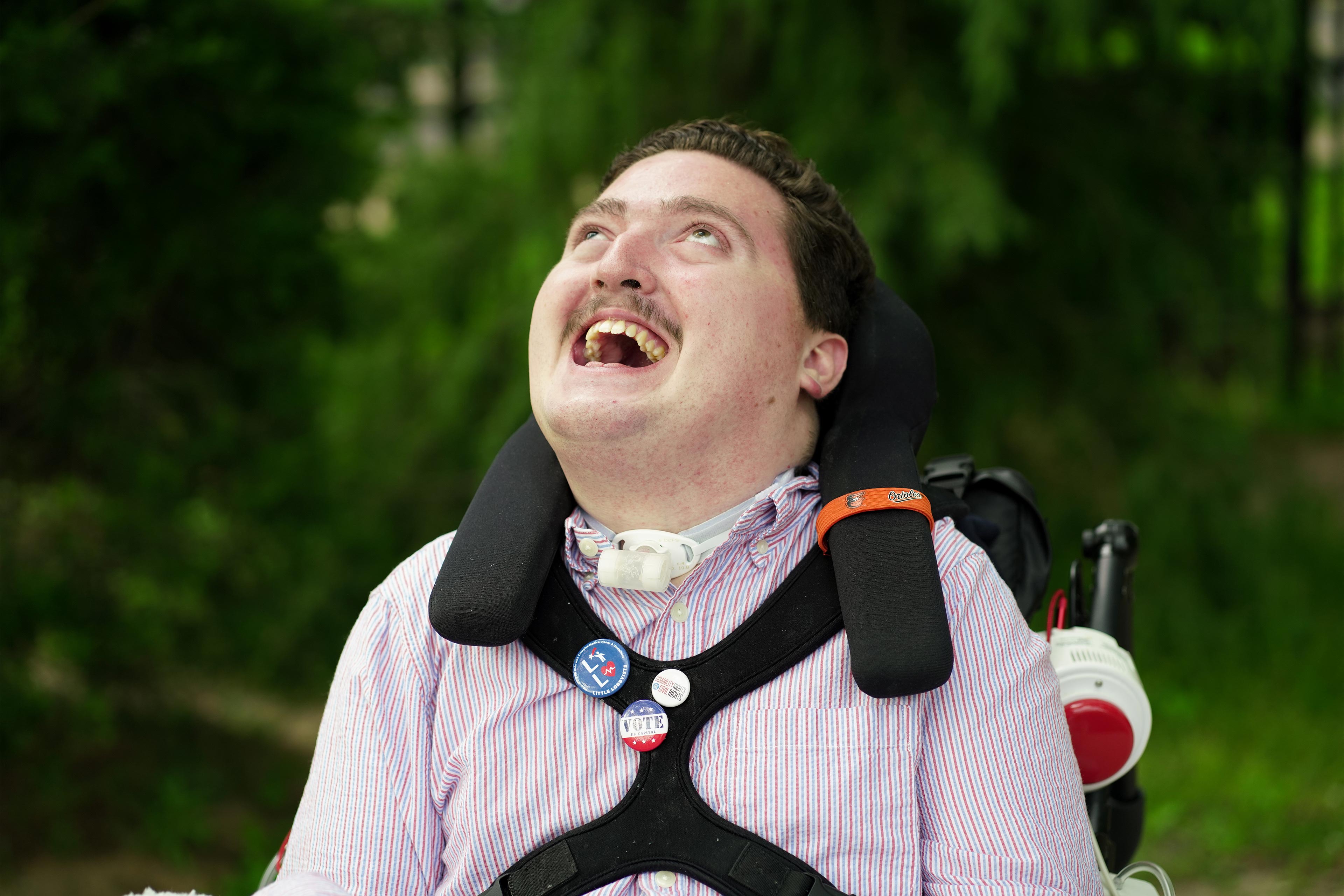 A photo shows Rob Stone posing for a portrait outside. He is sitting in a wheelchair.