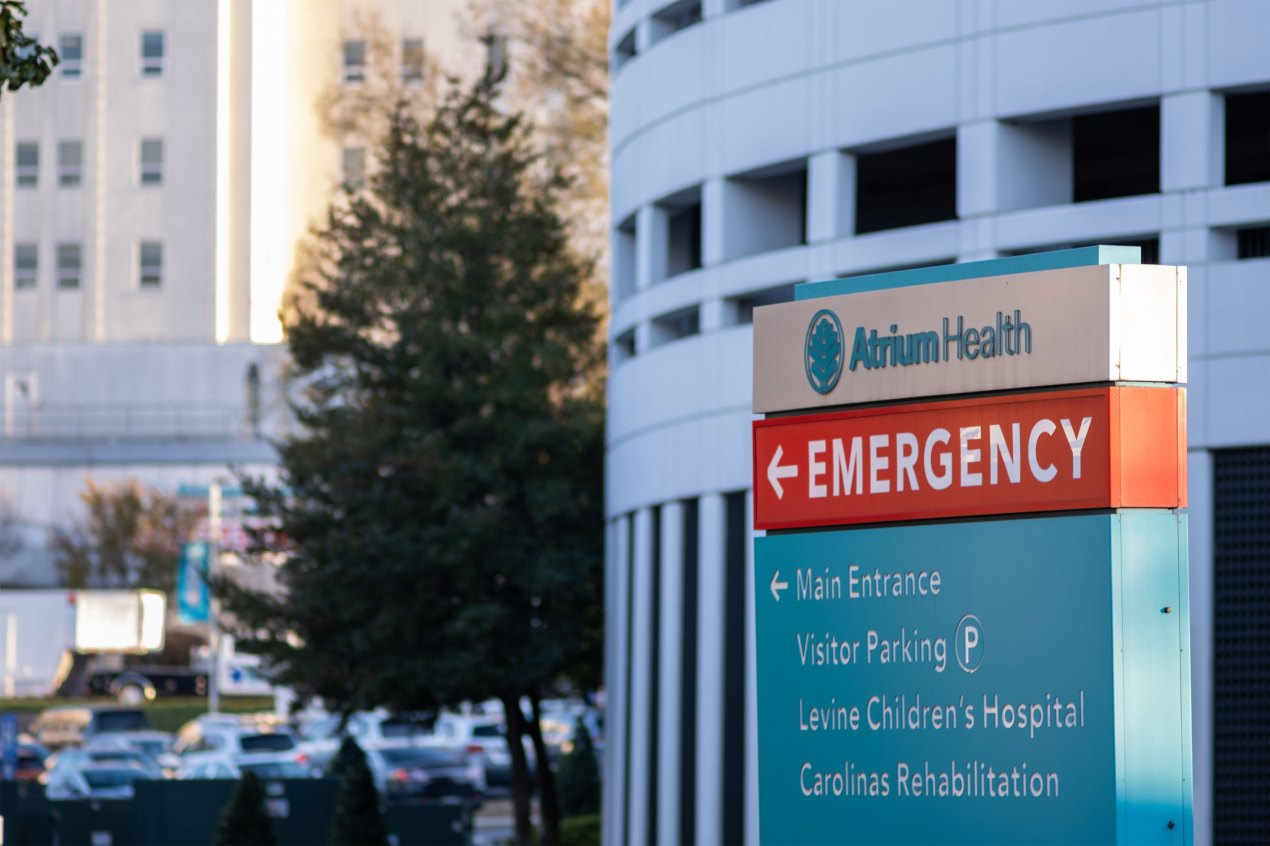 An Atrium Health sign directs drivers to the emergency department, was well as visitor parking and several other entrances.