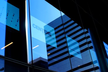 A photo shows Centene's logo on a TV screen inside an office building.