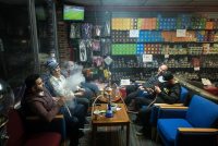 A photo shows patrons smoking hookah inside of a hookah lounge.