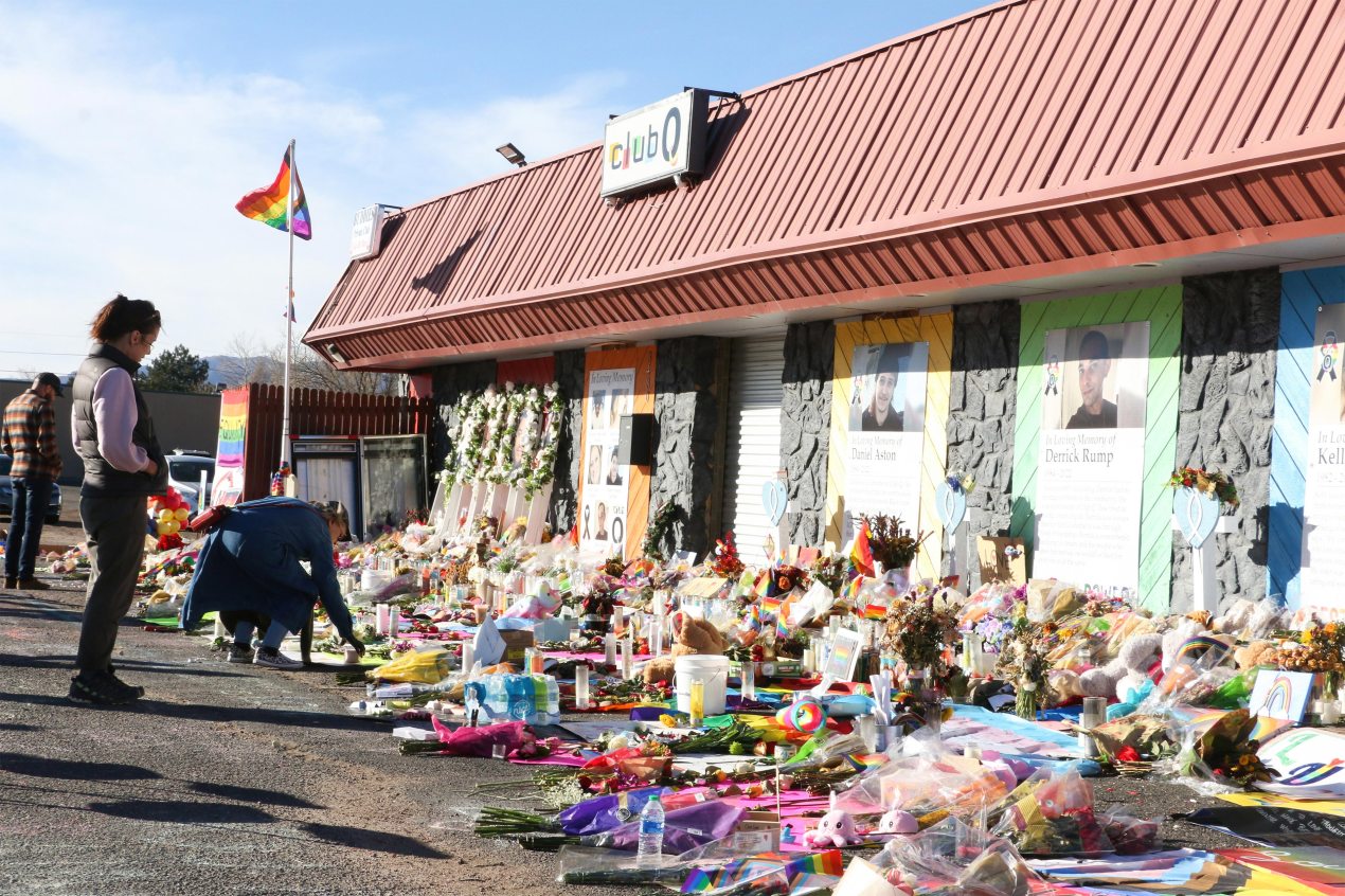 A photo shows bouquets of flowers, candles and stuffed animals displayed in front of the Club Q nightclub.