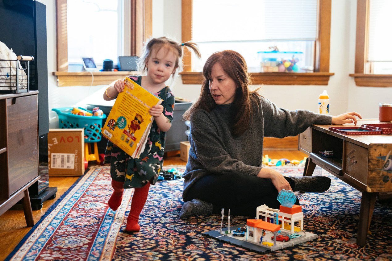 A photo shows Brenna Kearney sitting at home as her daughter, Joey, plays.