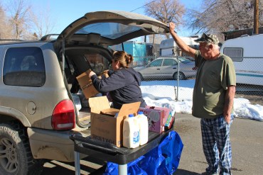 A photo shows Tammy King loading packages of food into the trunk of a vehicle.