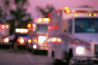 An out-of-focus image of several ambulances with their lights on.