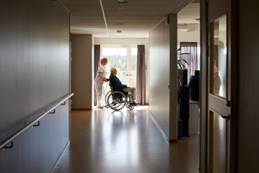 A photo shows a nursing home worker pushing a resident in a wheelchair.