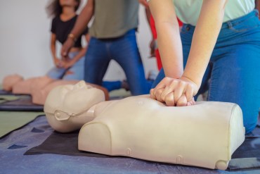 Students practice chest compressions on a dummy during CPR training.