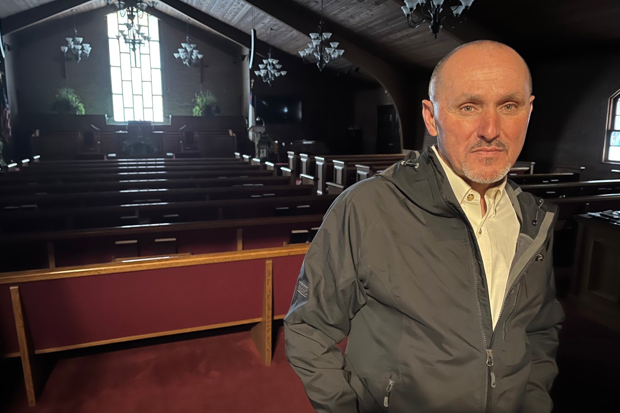 Paul White stands with his hands in the pockets of his jackets inside an empty church.