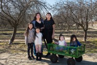 Carolina Morga Tapia stands outside in a park with her five children. Two of the youngest are sitting in a green wagon.