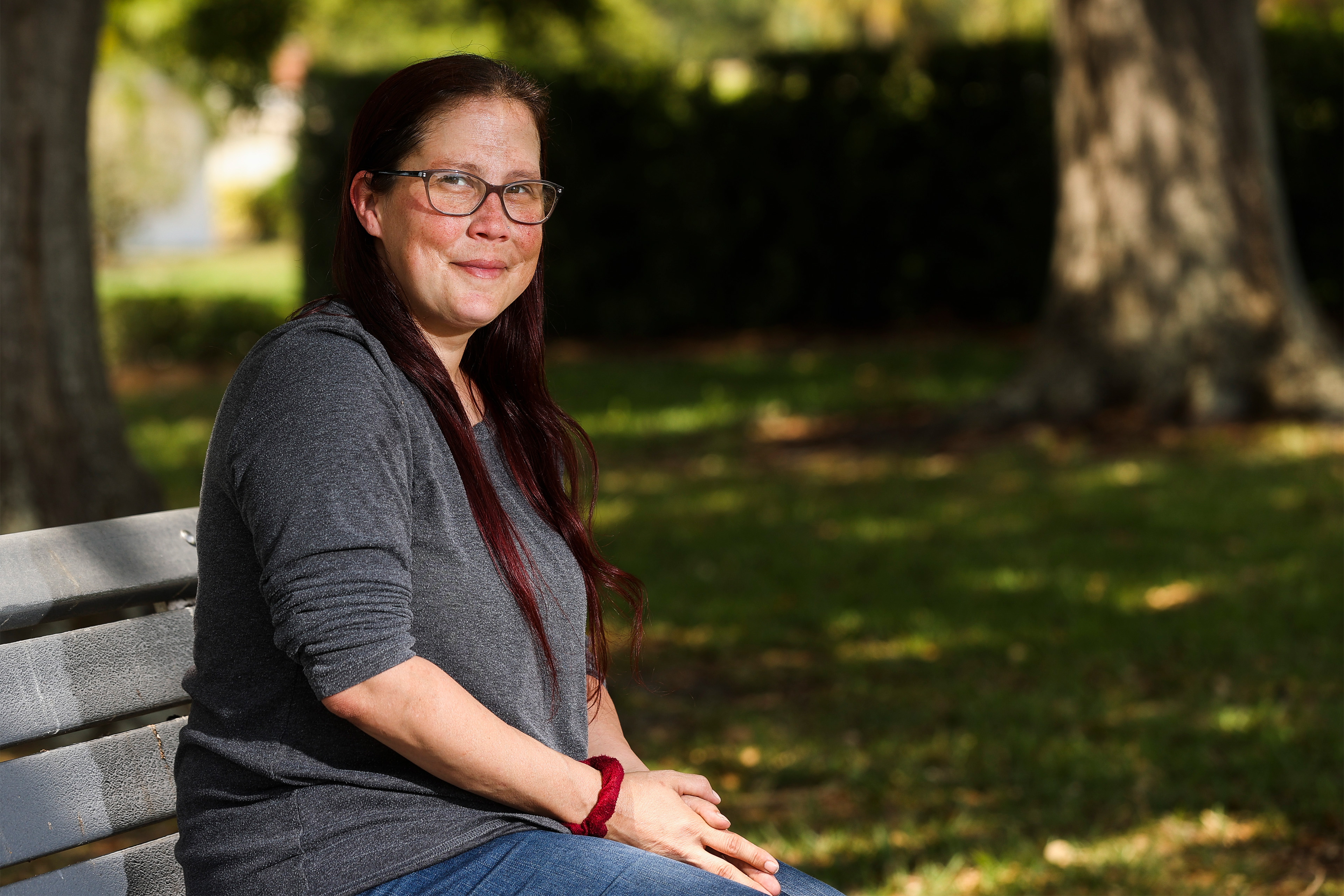 A photo of a woman sitting for a portrait on a bench outside.