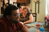 A photo of a woman and her husband sitting at home.