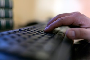 A photo of a hand typing on a computer keyboard.
