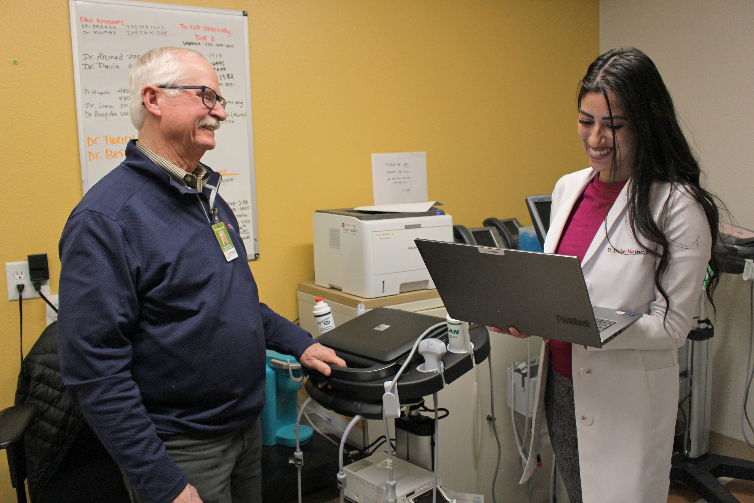 A photo of a Dr. Bridget Martinez speaking to her program's director inside an exam room.