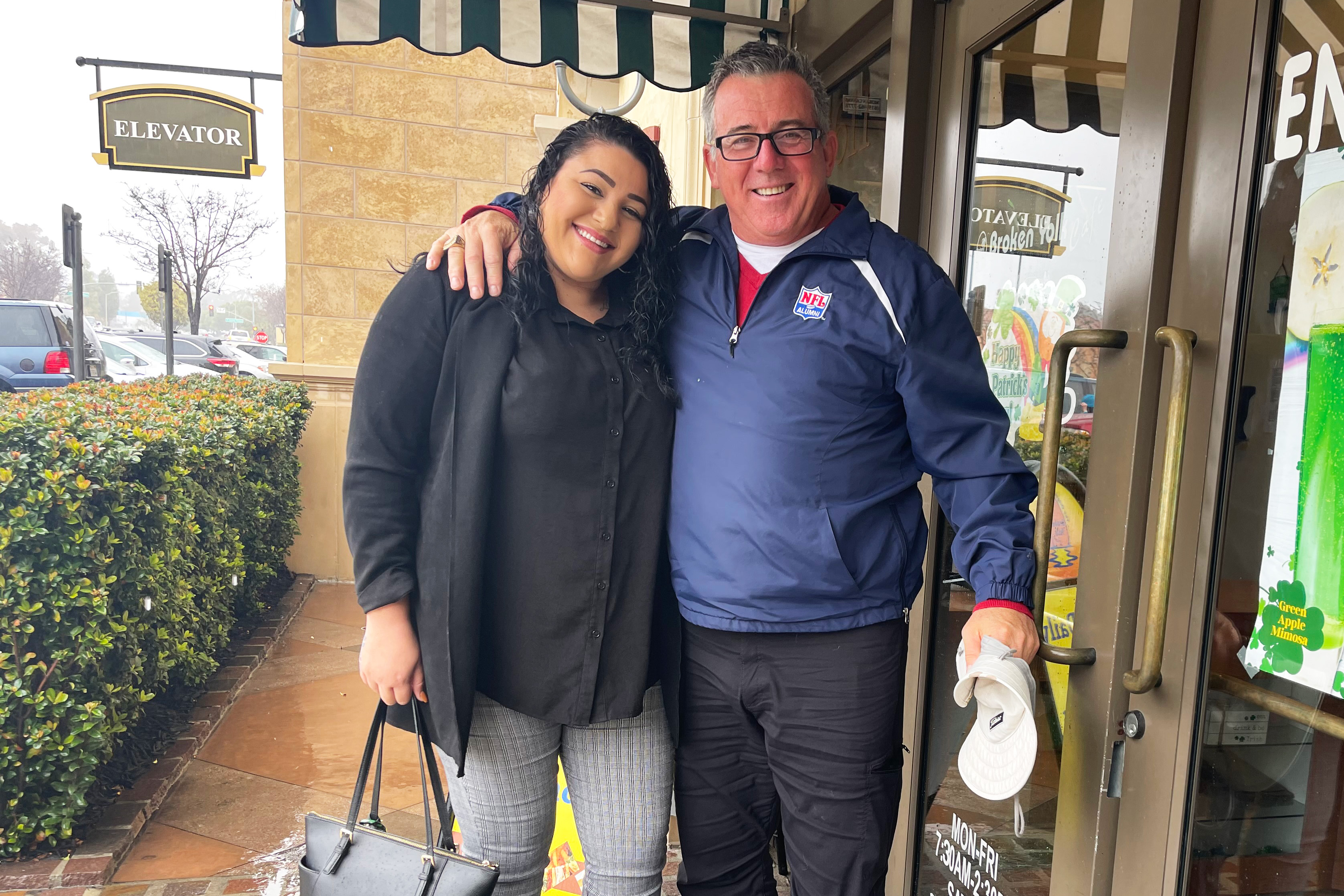 A photo of a woman and a man hugging outside of a restaurant.