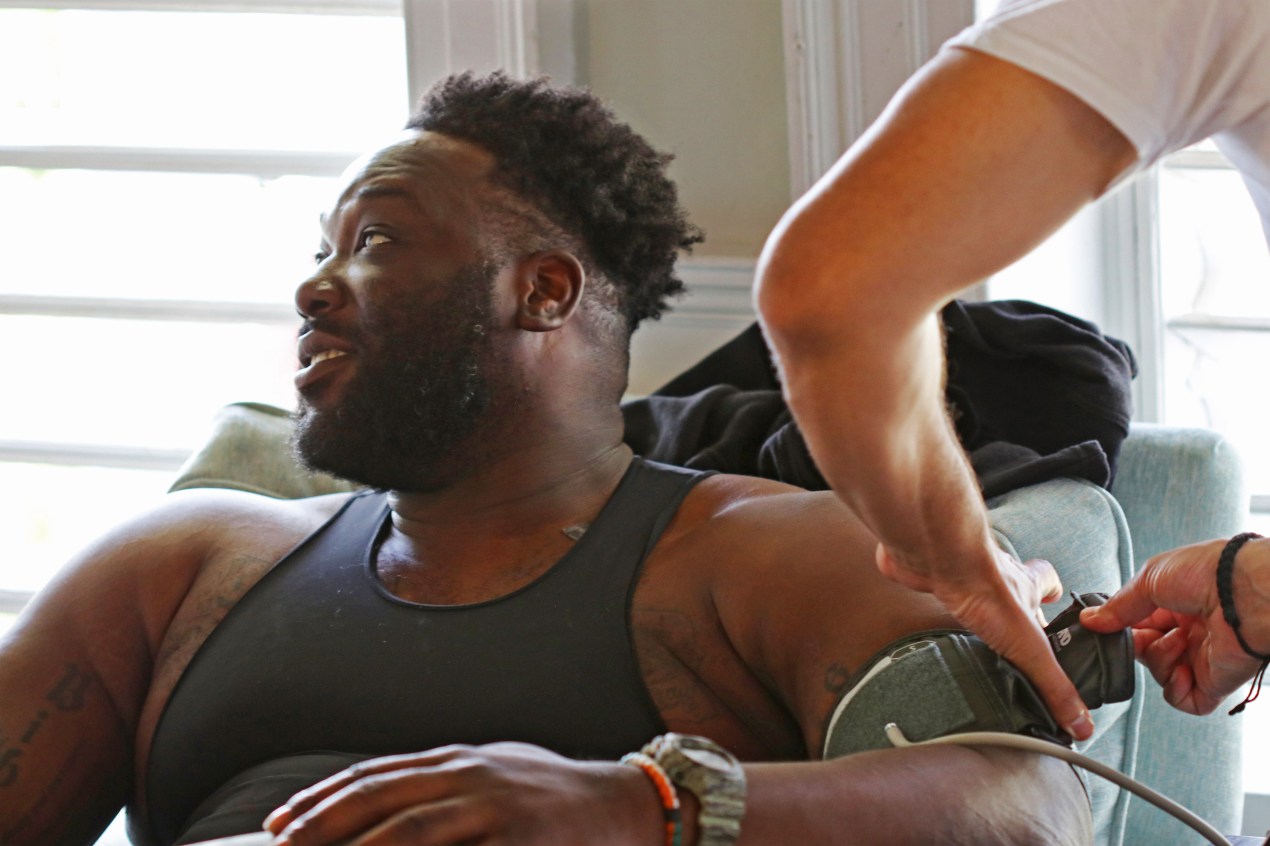 A photo of Justin Renfrow sitting as someone puts a blood pressure cuff on his arm.