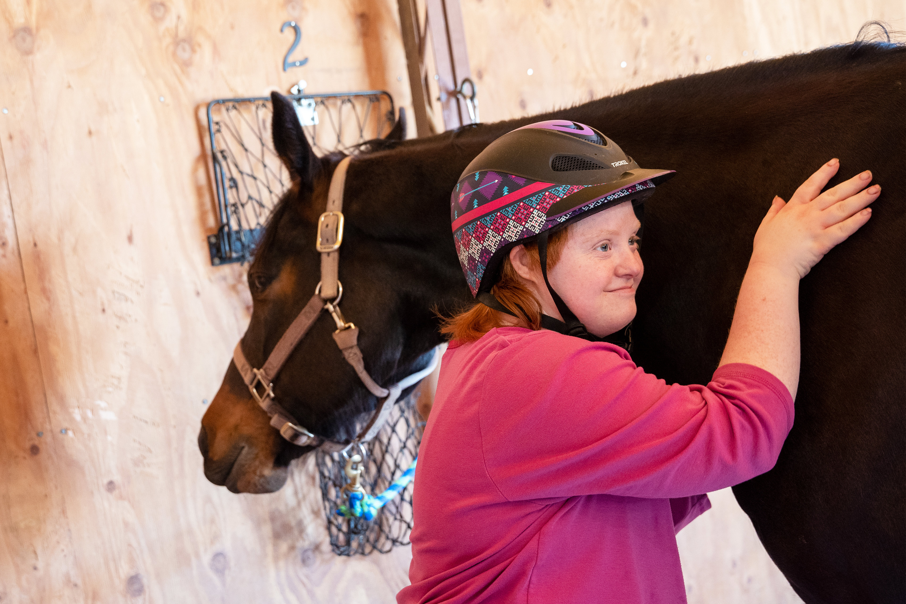 A photo of a young woman hugging a horse.