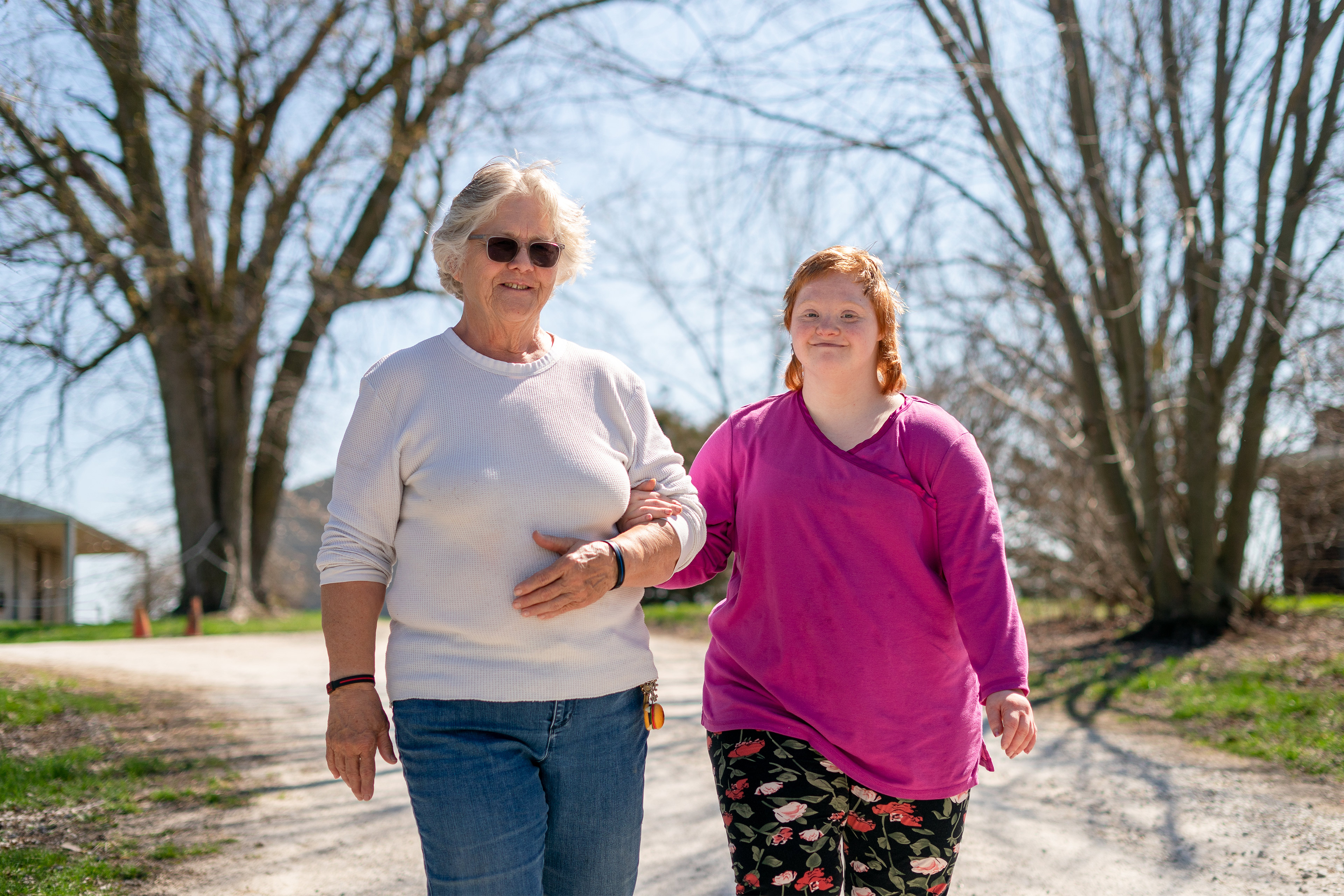 A photo of an older woman and her adult daughter posing for a portrait outdoors.