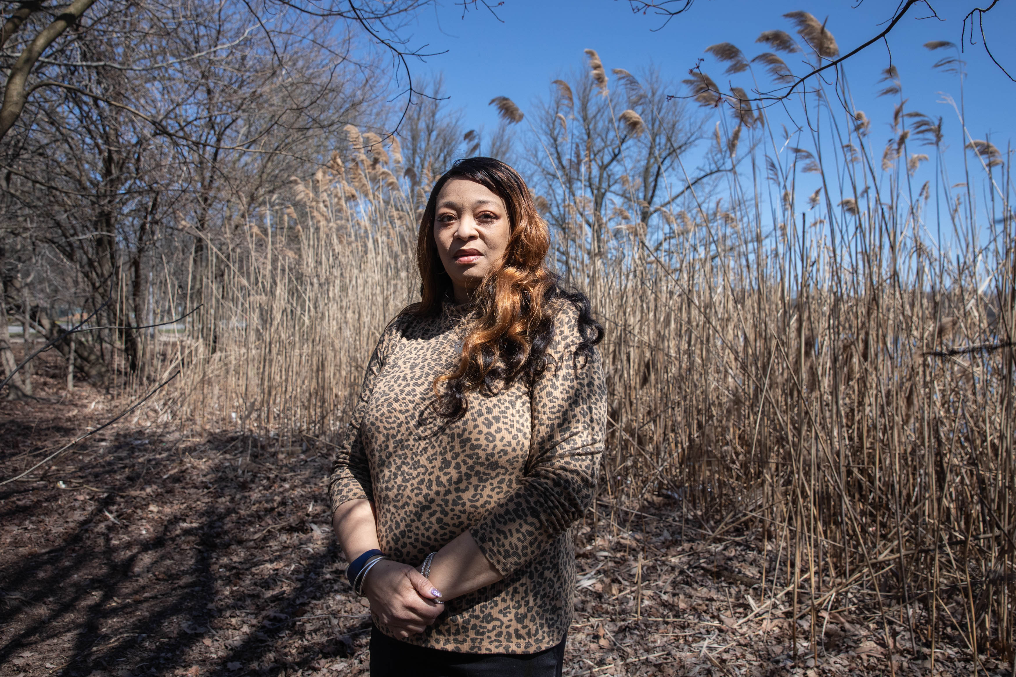 A photo of a woman posing for a portrait outside with plants behind her.