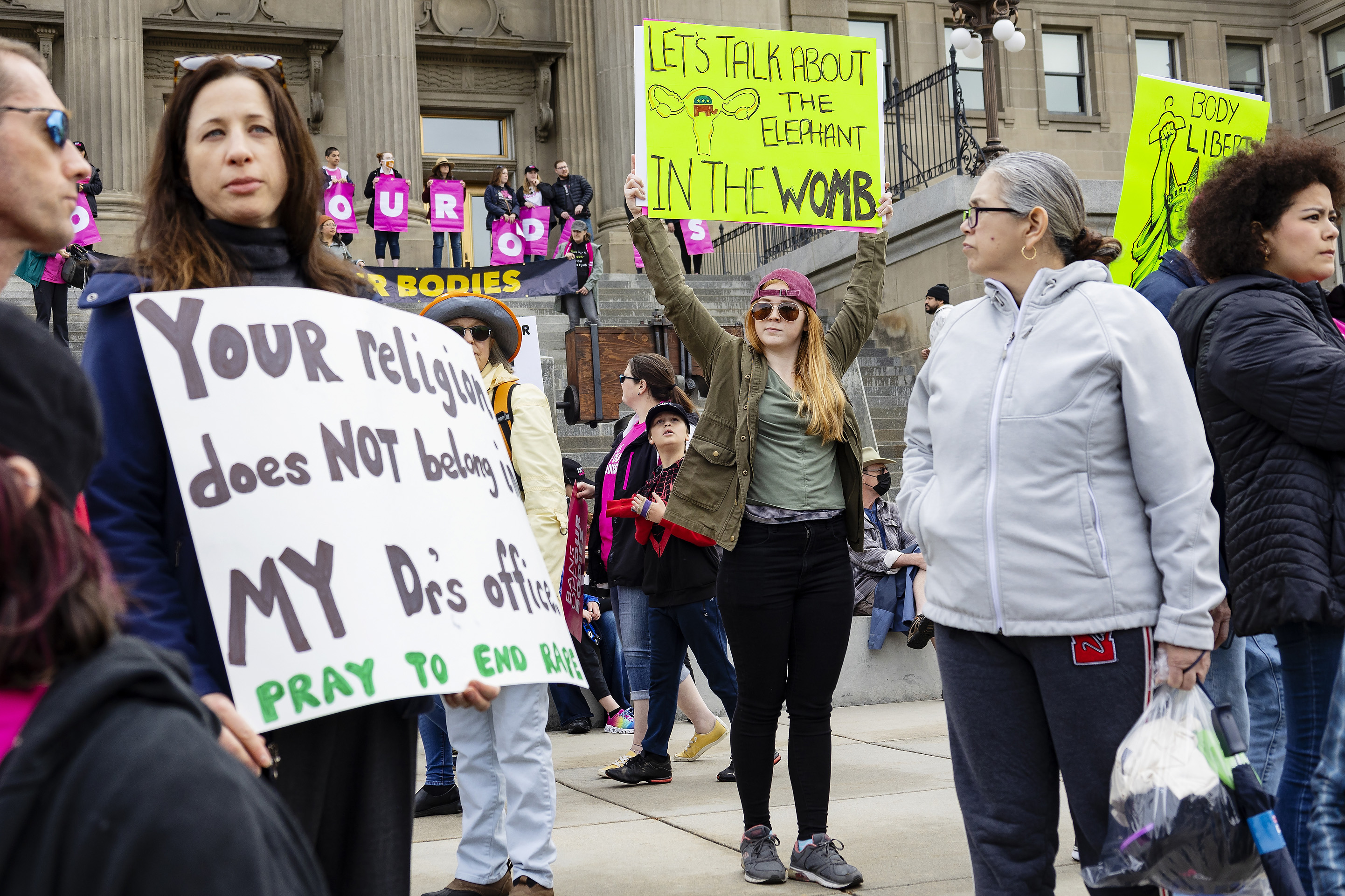 Protestuotojas laiko ženklą su Respublikonų partijos dramblio simboliu gimdos kontūre, kuriame parašyta: "Pakalbėkime apie dramblį įsčiose," per Planned Parenthood mitingą už abortų teises Aidaho valstijos rūmuose 2022 m. gegužės 14 d.