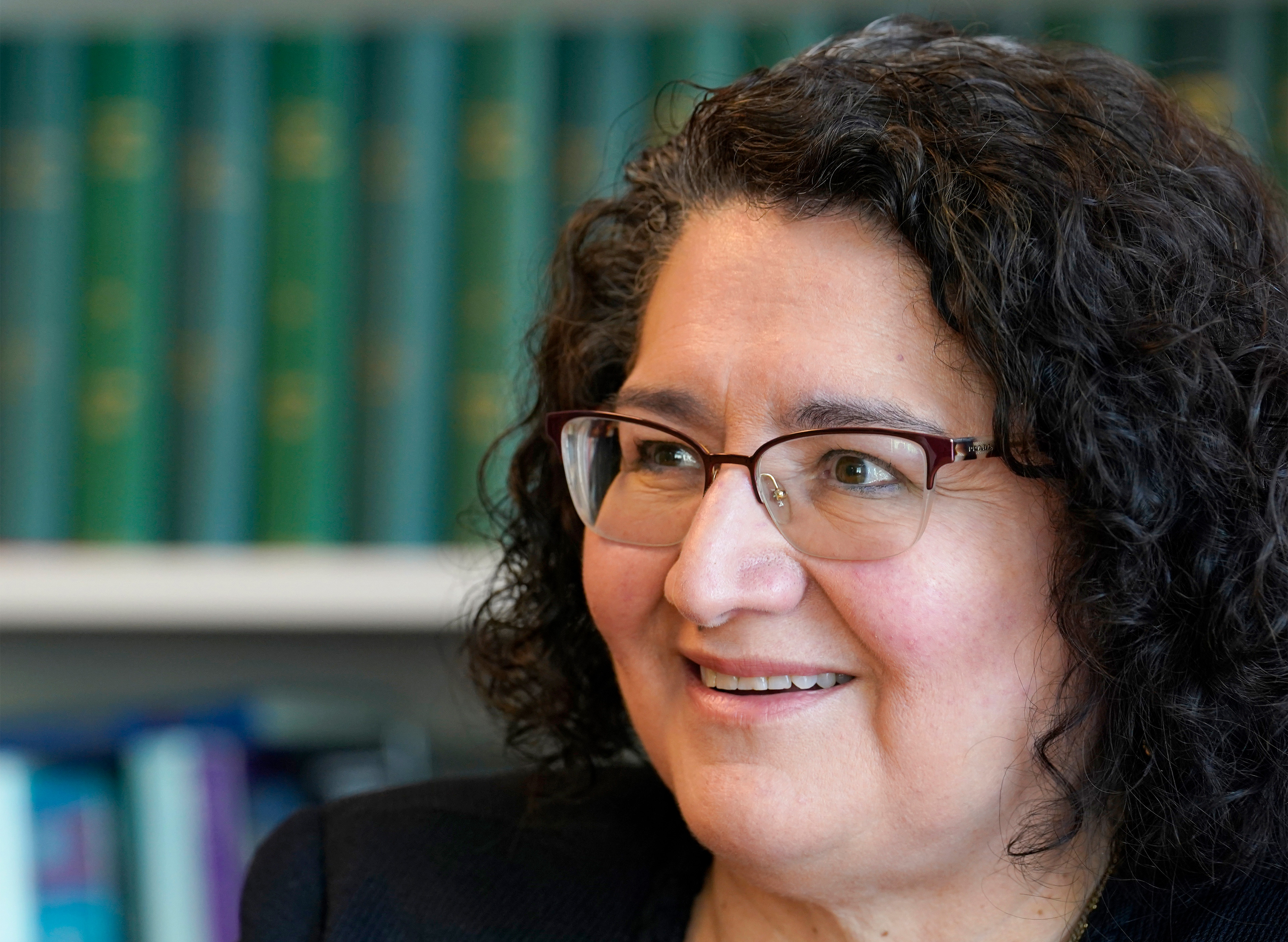 A photo of Carolina Reyes in front of a bookshelf indoors.