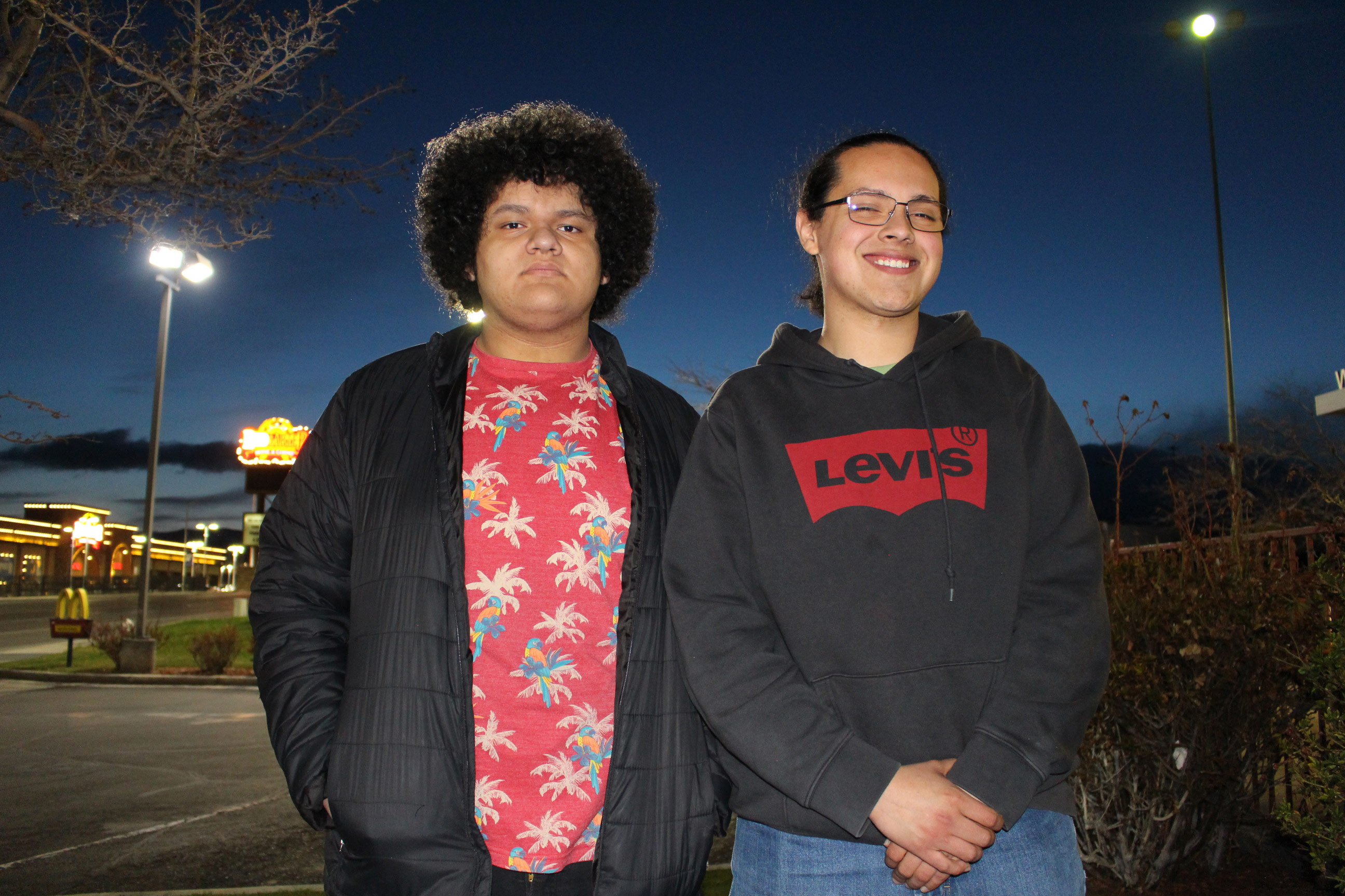 A photograph of two brothers posing for a photograph collectively outside at evening.
