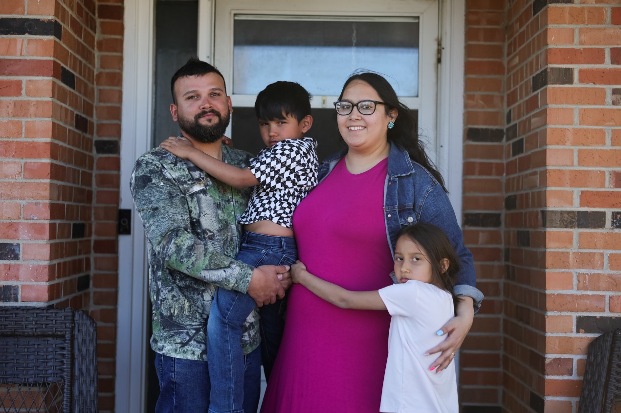 Cloie Davila, her daughter, Amelia, her husband, Joshua, and her son, Noah, stand outside their home in Clayton, New Mexico. Cloie is visibly pregnant.