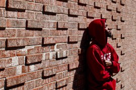 A photo of Erin Brown posing for a photo by leaning on a brick wall.