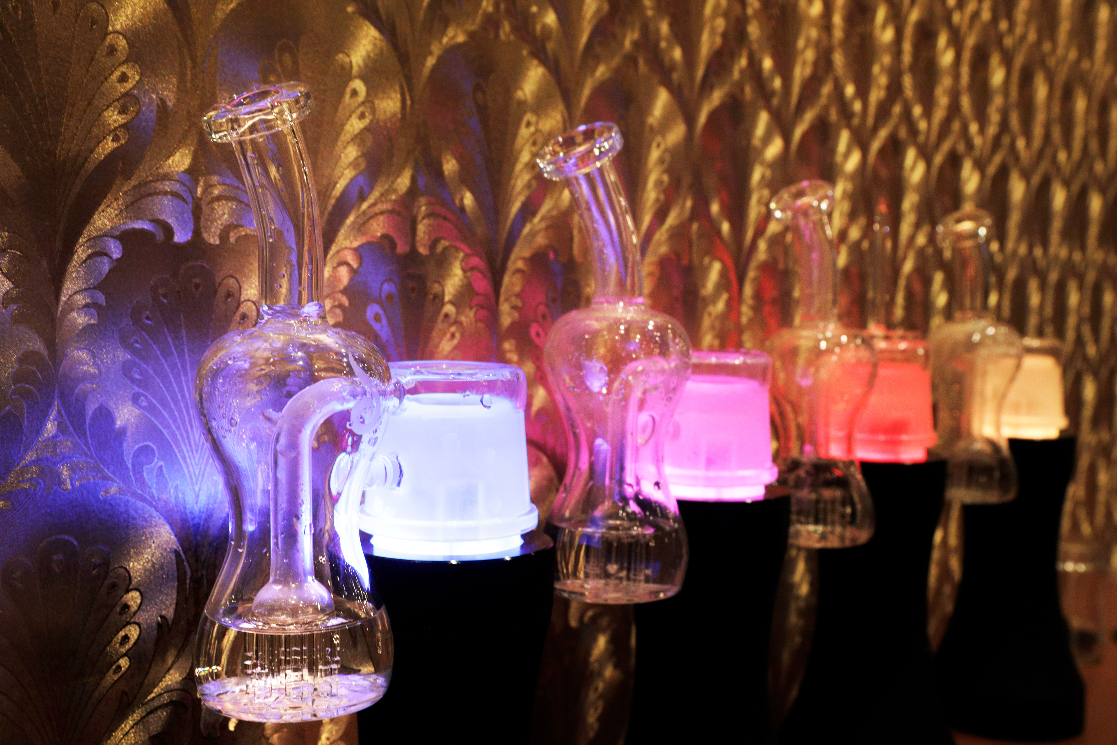A photo of glass dab rigs used to consume THC concentrate backed by colorful lights.