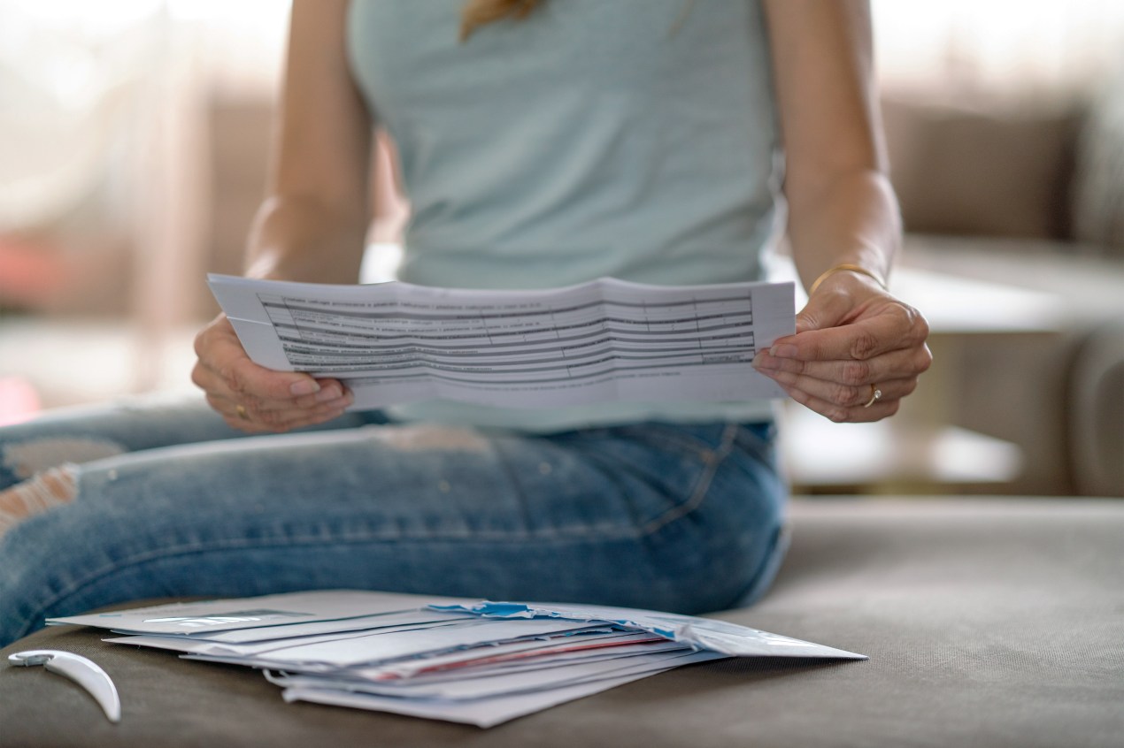 A photo of a woman looking over paperwork she's received in the mail.