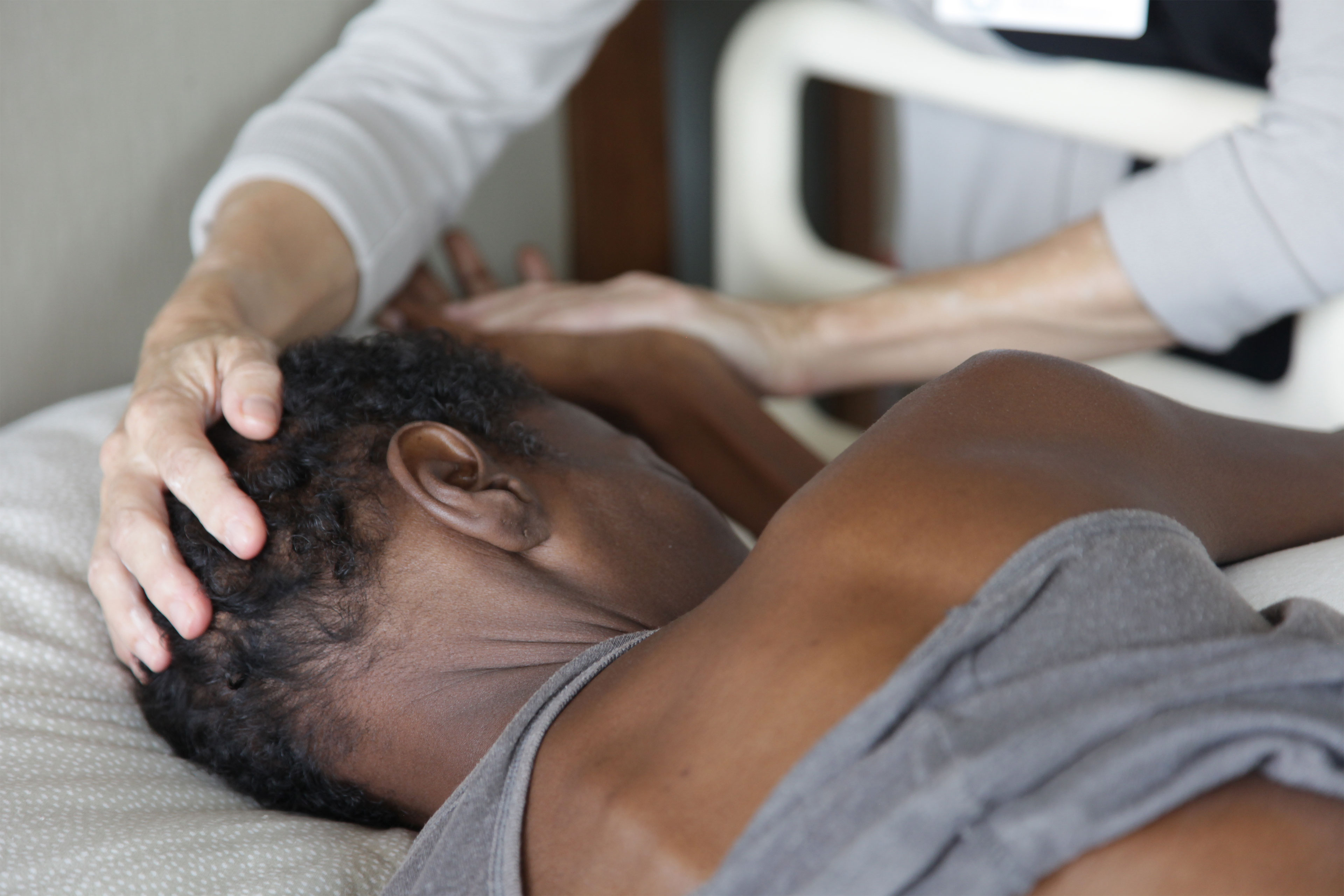 A photo of a woman lying down and receiving a head massage.