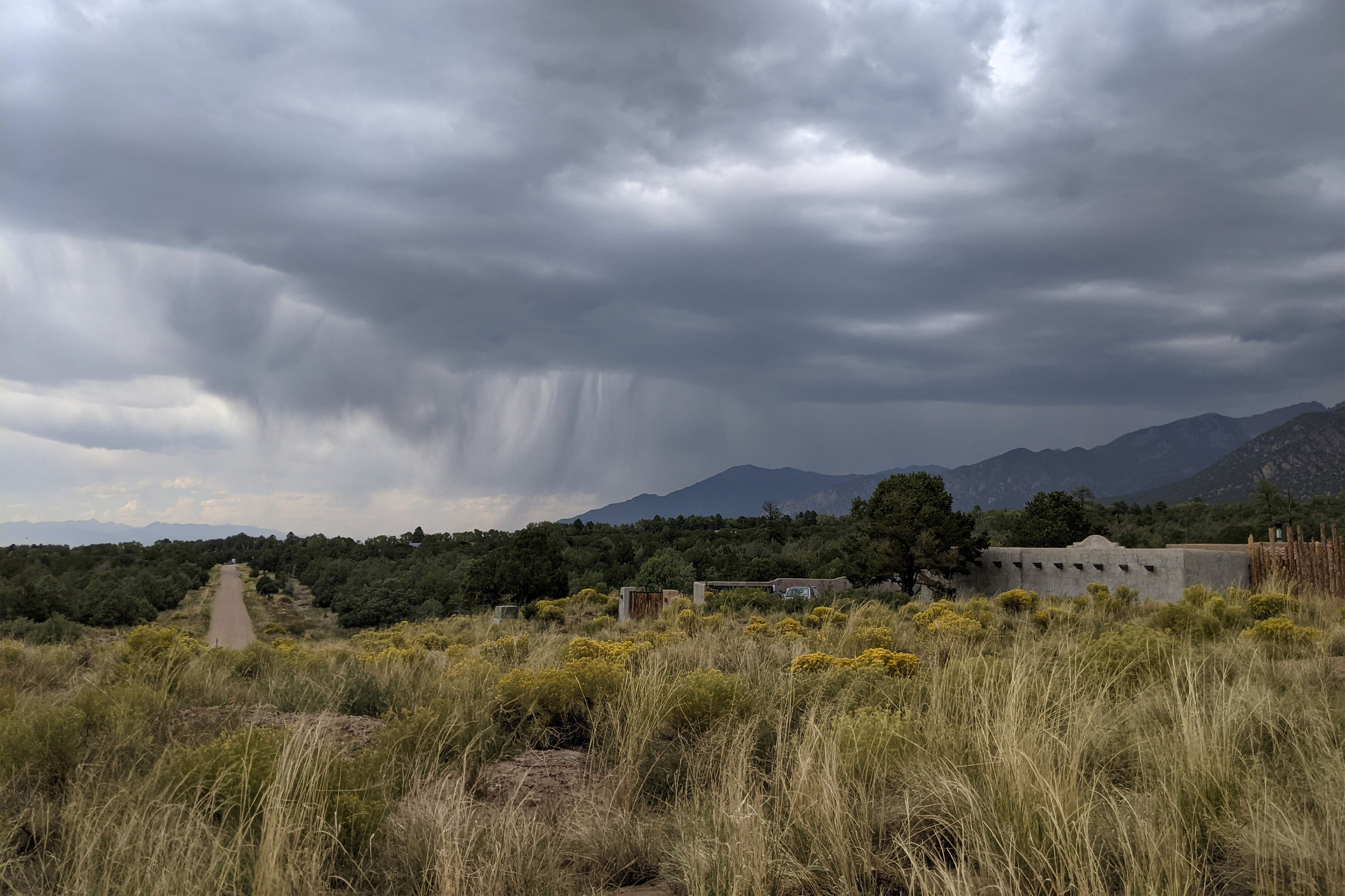 A photo of dark storm clouds hovering over mountains seen in the distance.