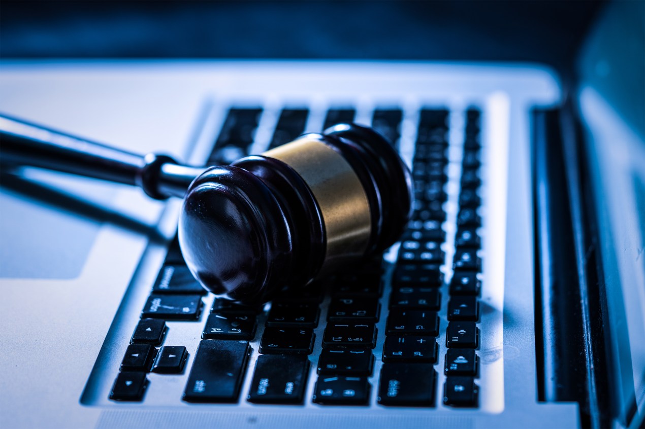 A photo of a judge's gavel resting on a laptop.