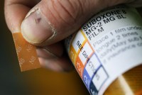 A photo of a patient holding a small strip of film next to a prescription bottle.