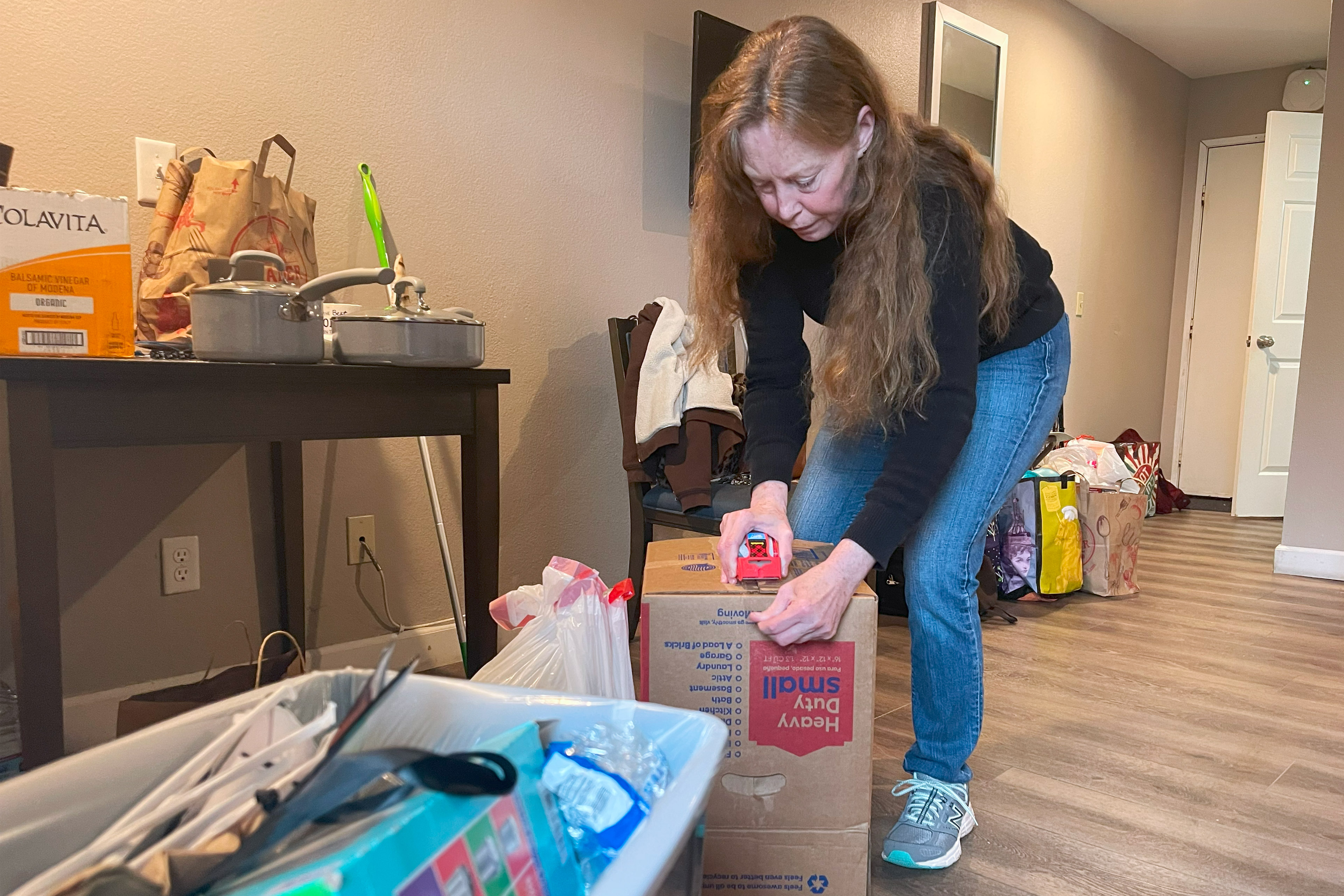 A photo of Annie Malloy taping up a box while packing away things to move.