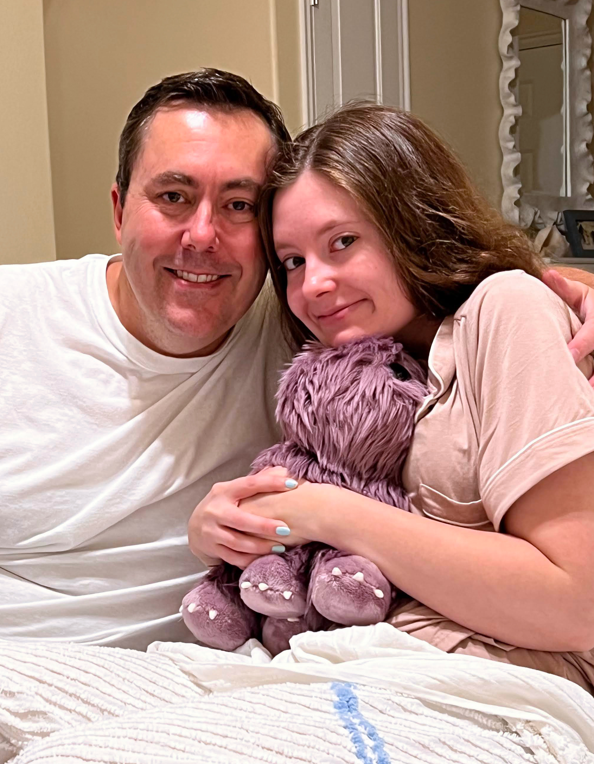 A photo of Isabella McDonald sitting next to her father while holding a stuffed animal.