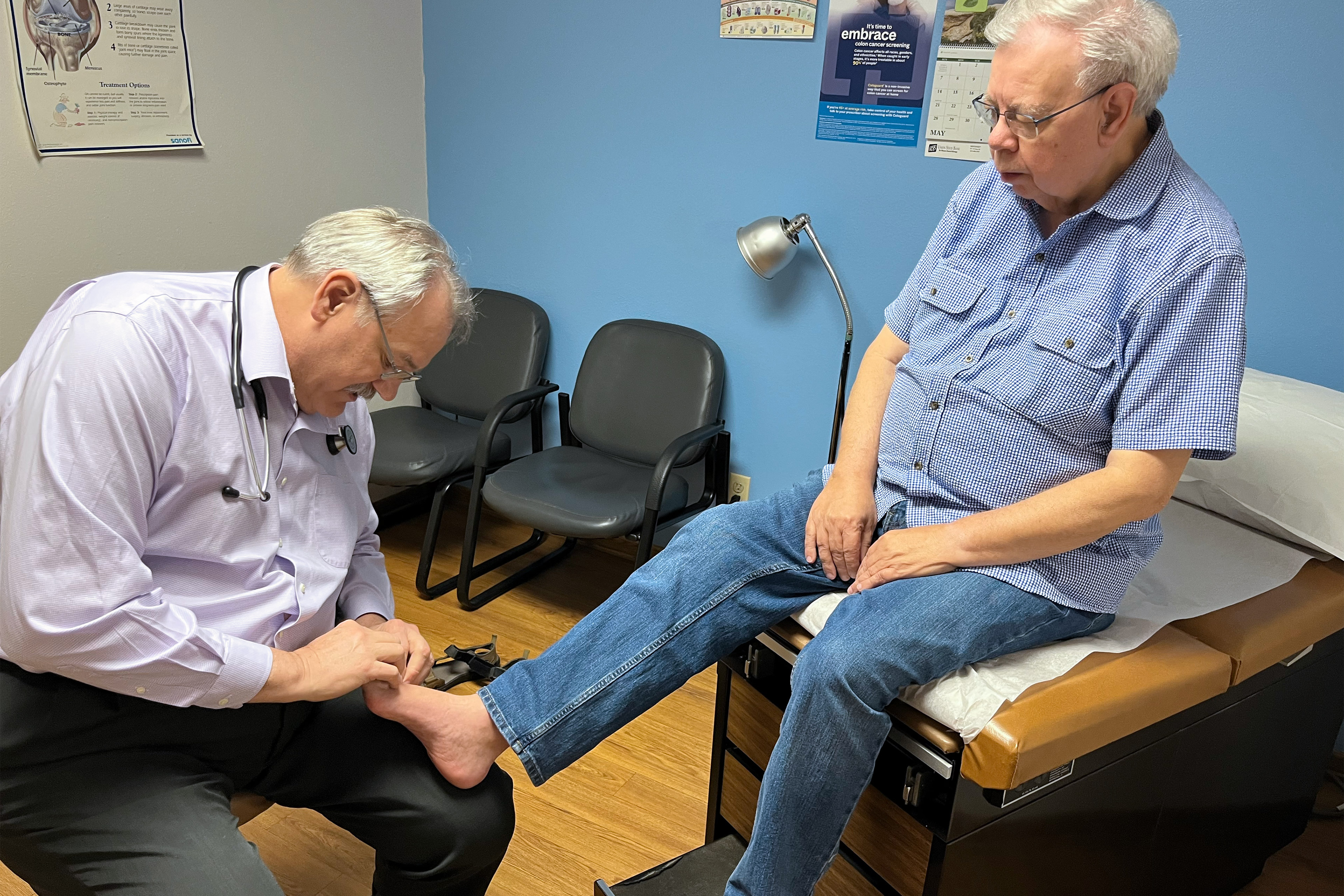 A photo of a doctor examining a male patient's foot.