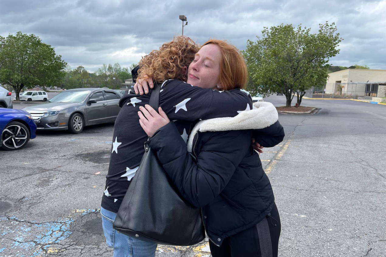 A photo of two women hugging outside.