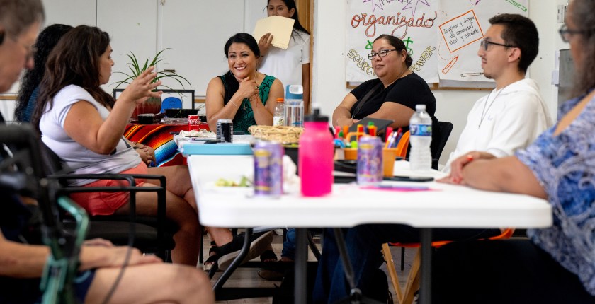 A photo of a community members sitting around a table at a meeting.
