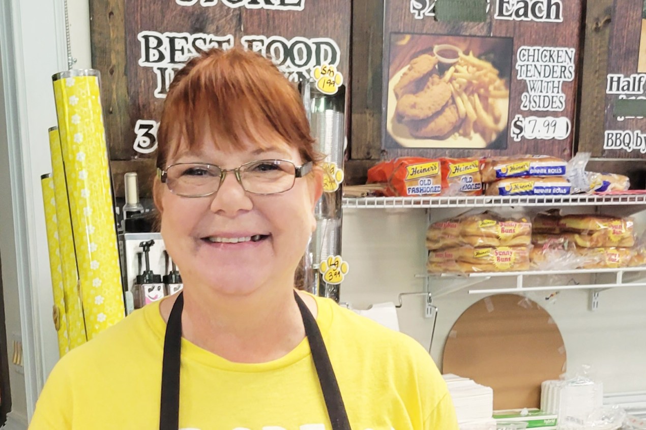 A photo of a woman inside of a store smiling for a photo.