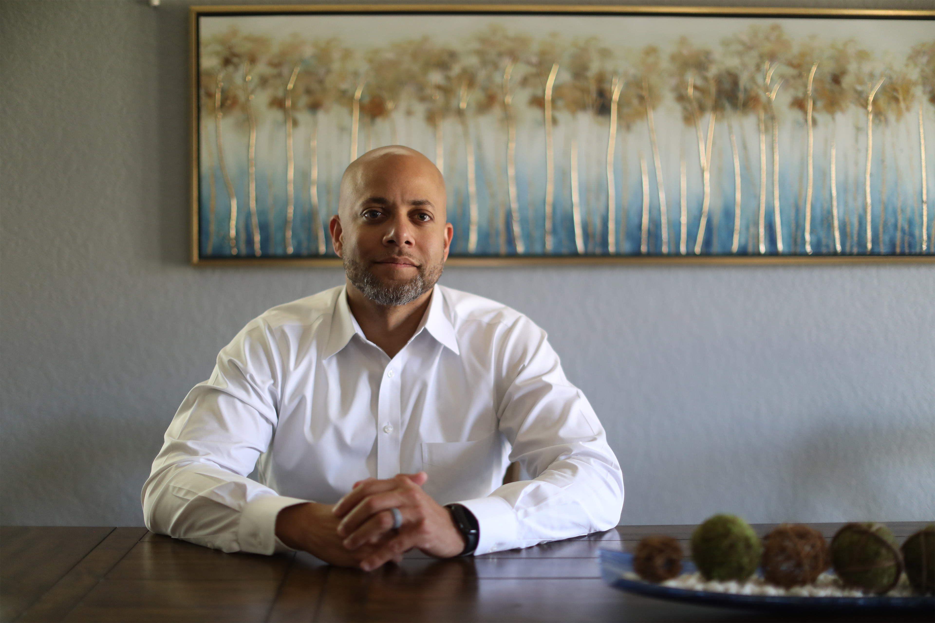 A photo of a man posing for a portrait and sitting at the table.