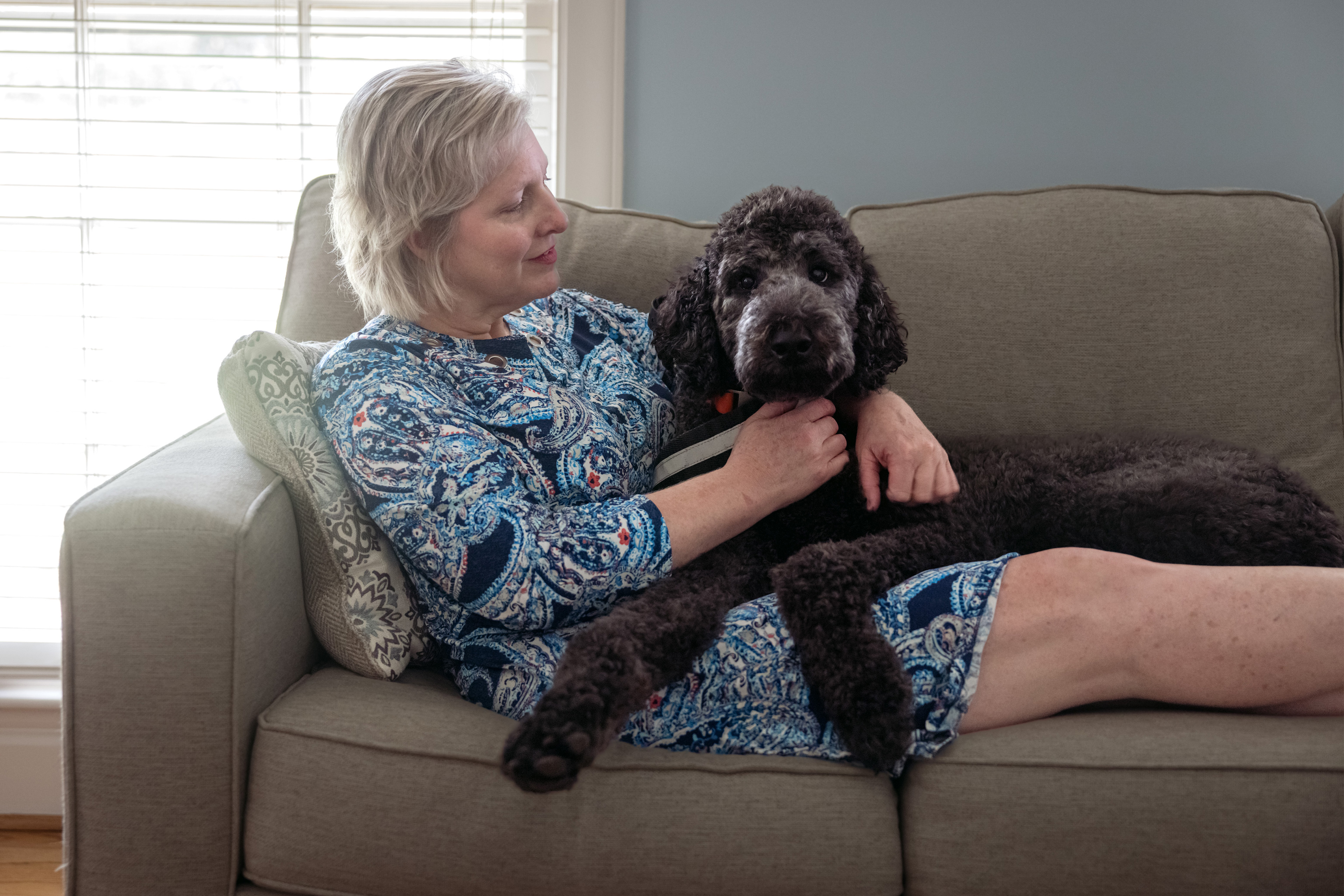 Photo of a woman lying on a couch with her dog.